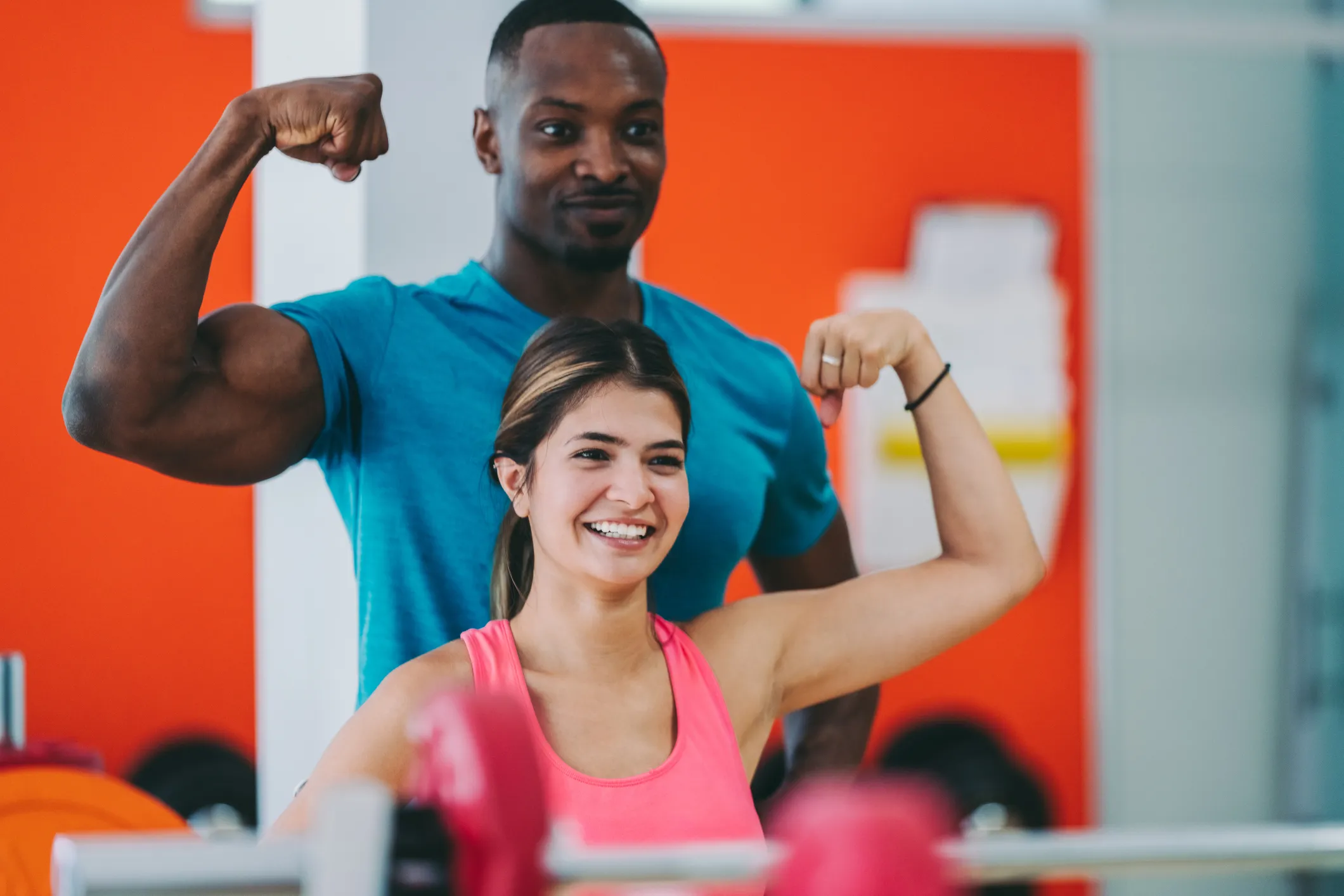 woman shows muscle with personal trainer