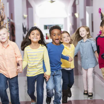 school age children holding hands in hallway